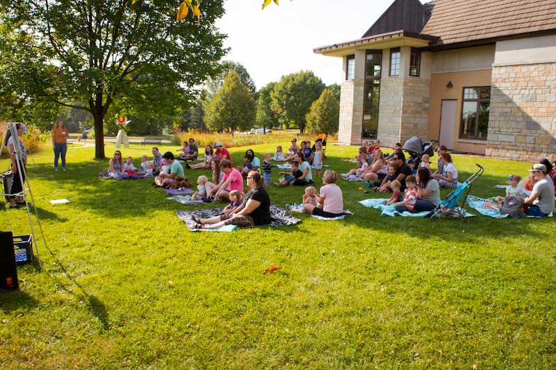 Families gathered around a teacher for a Music Avenue class